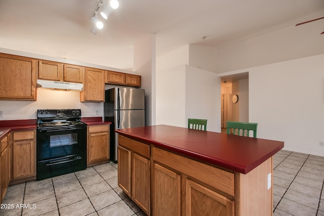 kitchen with a kitchen island, stainless steel refrigerator, light tile patterned floors, track lighting, and black / electric stove