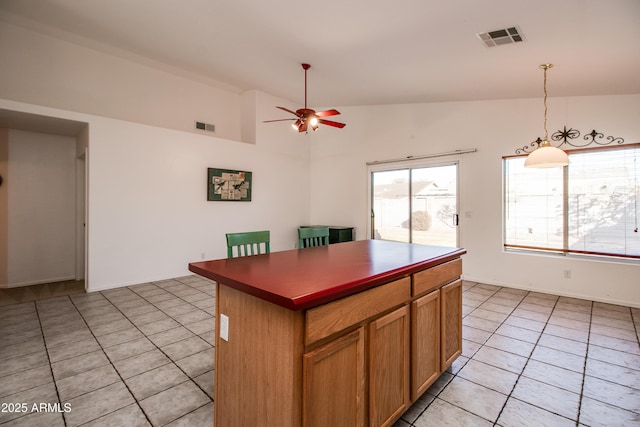 kitchen featuring lofted ceiling, a center island, hanging light fixtures, light tile patterned floors, and ceiling fan