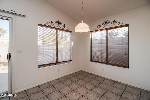 unfurnished dining area featuring vaulted ceiling, a wealth of natural light, and tile patterned floors