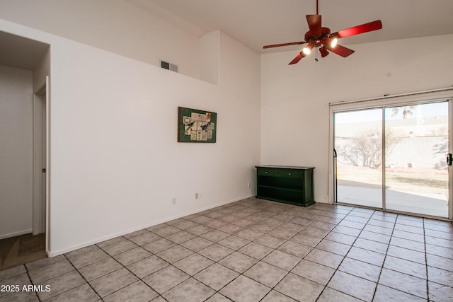 unfurnished living room featuring a towering ceiling, light tile patterned floors, and ceiling fan