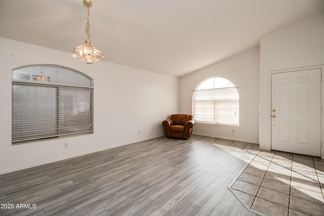 interior space with lofted ceiling, hardwood / wood-style floors, and an inviting chandelier