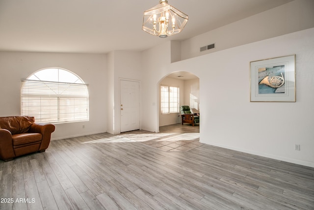 interior space featuring high vaulted ceiling, an inviting chandelier, and light hardwood / wood-style flooring