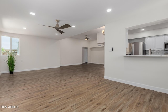 unfurnished living room featuring ceiling fan and hardwood / wood-style flooring