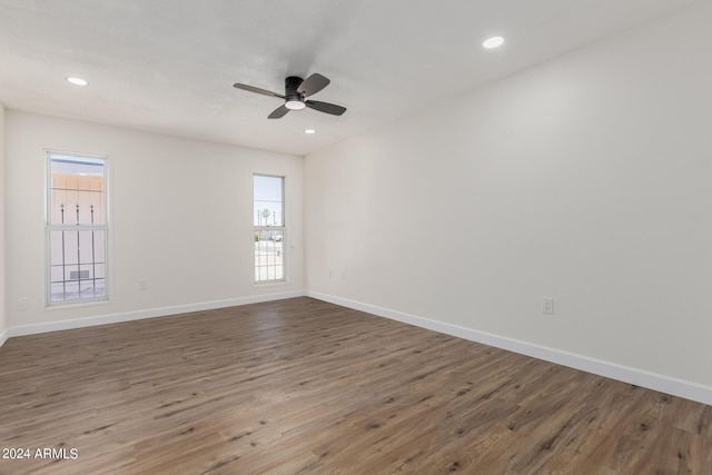 empty room with ceiling fan, a wealth of natural light, and hardwood / wood-style floors