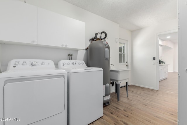 laundry area featuring a textured ceiling, cabinets, sink, independent washer and dryer, and light hardwood / wood-style flooring