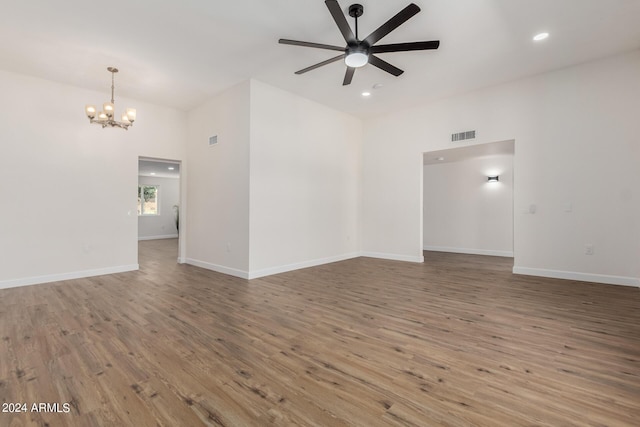 empty room with ceiling fan with notable chandelier and wood-type flooring