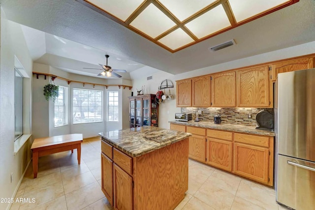 1704 S Barkley Rd, Apache Junction, AZ 85119 - kitchen featuring freestanding refrigerator, a kitchen island, tasteful backsplash, light stone countertops, and ceiling fan