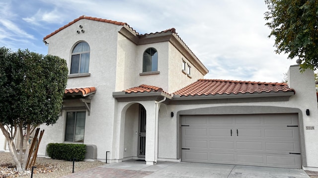 mediterranean / spanish-style house featuring a tile roof, driveway, a chimney, and stucco siding