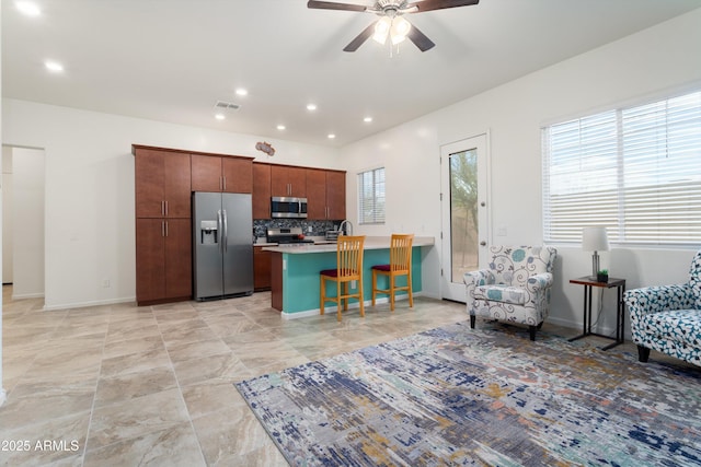 kitchen featuring visible vents, a kitchen breakfast bar, tasteful backsplash, stainless steel appliances, and light countertops