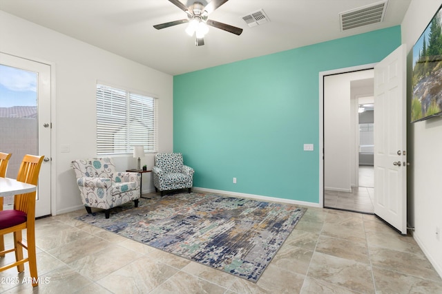 living area with visible vents, baseboards, and a ceiling fan