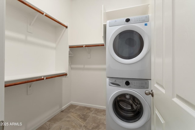 laundry room with laundry area, baseboards, and stacked washing maching and dryer