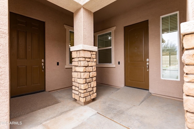 view of exterior entry featuring stone siding and stucco siding