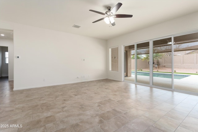 spare room featuring visible vents, a ceiling fan, and baseboards