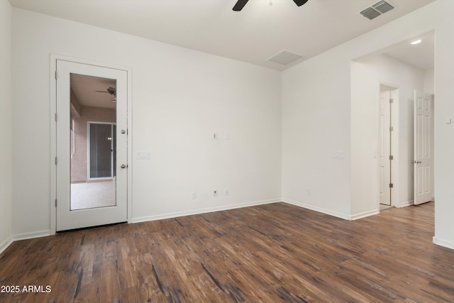 spare room featuring dark wood finished floors, visible vents, ceiling fan, and baseboards