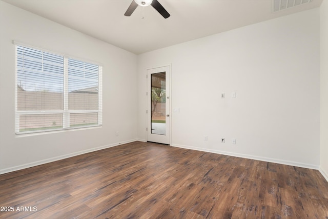 empty room with visible vents, a ceiling fan, baseboards, and dark wood-style flooring