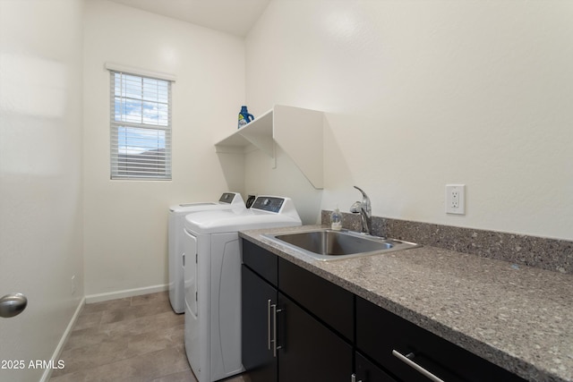 laundry area with cabinet space, separate washer and dryer, baseboards, and a sink