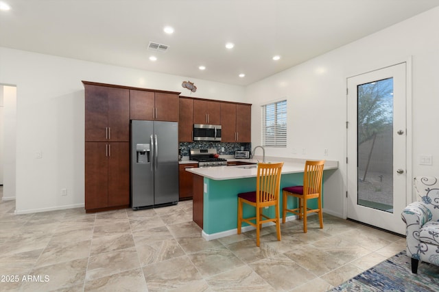 kitchen with visible vents, a peninsula, a sink, stainless steel appliances, and light countertops