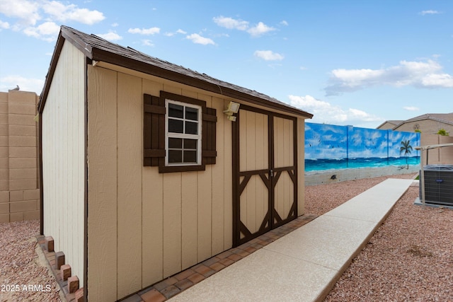 view of shed featuring central air condition unit and fence