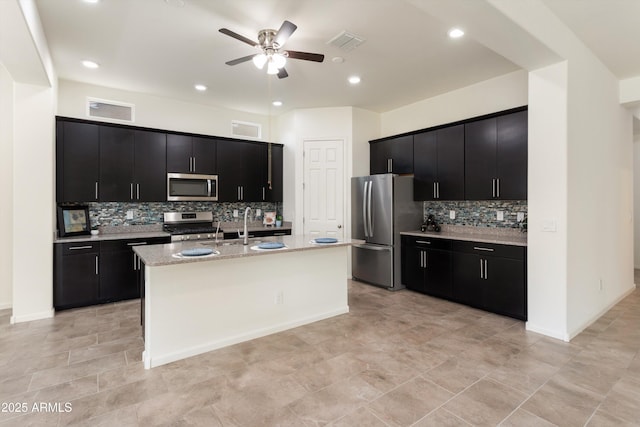 kitchen featuring a center island with sink, visible vents, appliances with stainless steel finishes, and dark cabinetry