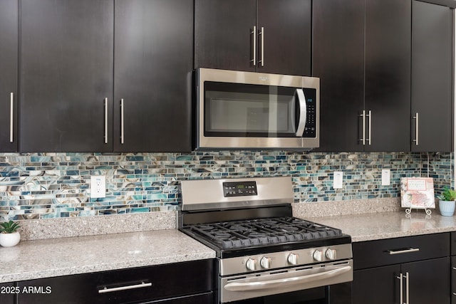 kitchen with tasteful backsplash, appliances with stainless steel finishes, and dark cabinetry