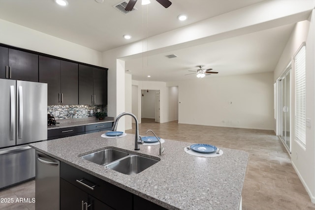 kitchen with visible vents, open floor plan, decorative backsplash, appliances with stainless steel finishes, and a sink