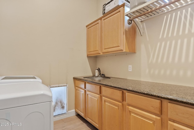 laundry area featuring sink, washer and clothes dryer, and cabinets