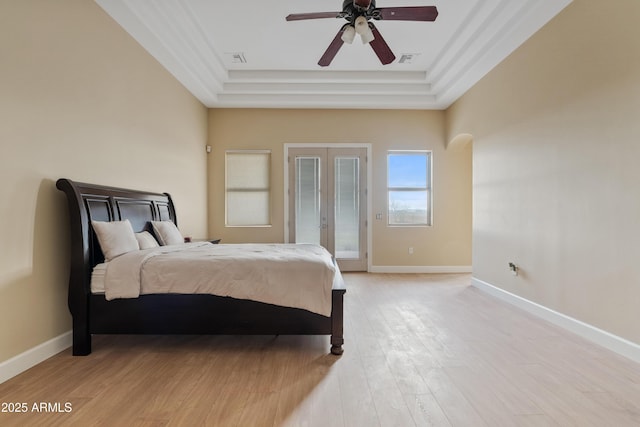 bedroom with access to outside, ceiling fan, a tray ceiling, light hardwood / wood-style floors, and french doors