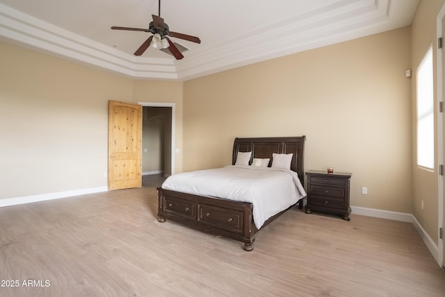 bedroom with a raised ceiling, ceiling fan, and light hardwood / wood-style floors