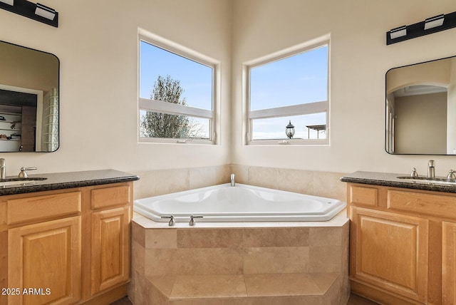 bathroom with vanity and tiled tub