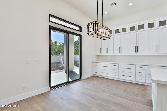 unfurnished dining area with an inviting chandelier and light hardwood / wood-style floors