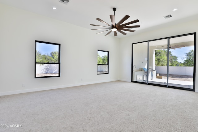 spare room with ceiling fan, light carpet, and plenty of natural light