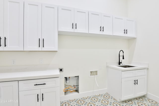 clothes washing area featuring hookup for an electric dryer, cabinets, sink, and hookup for a washing machine