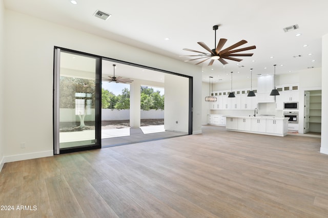 unfurnished living room featuring sink and light hardwood / wood-style flooring