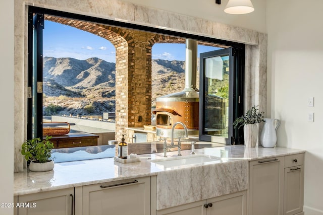 kitchen with a mountain view, sink, white cabinets, and light stone counters