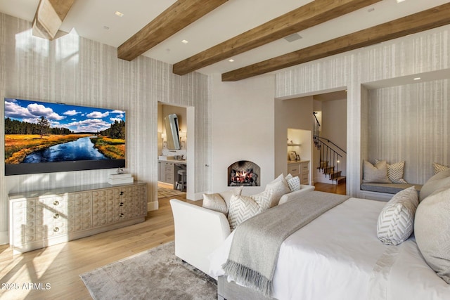 bedroom with beam ceiling, a fireplace, and light hardwood / wood-style floors