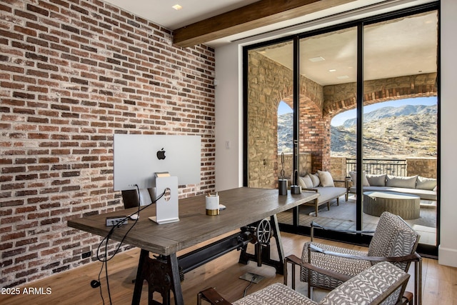 dining space with beamed ceiling, brick wall, a mountain view, and light hardwood / wood-style flooring