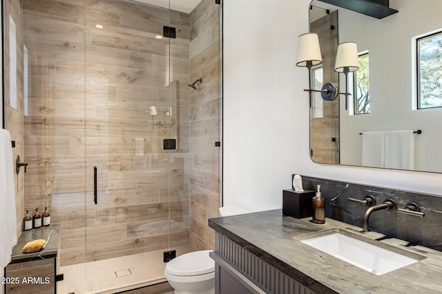 bathroom featuring vanity, decorative backsplash, a shower with door, and toilet