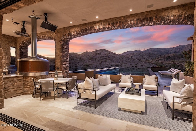 patio terrace at dusk featuring area for grilling, a mountain view, and an outdoor hangout area