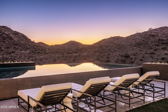 patio terrace at dusk featuring a water and mountain view