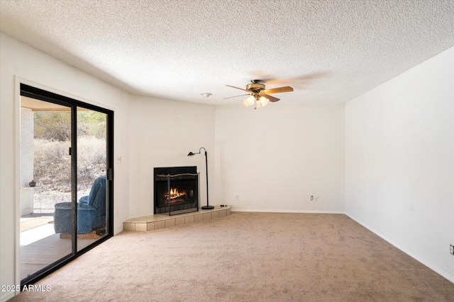 unfurnished living room with carpet floors, ceiling fan, a textured ceiling, and a tile fireplace