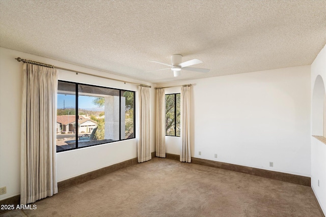 spare room featuring light carpet, a textured ceiling, a ceiling fan, and baseboards