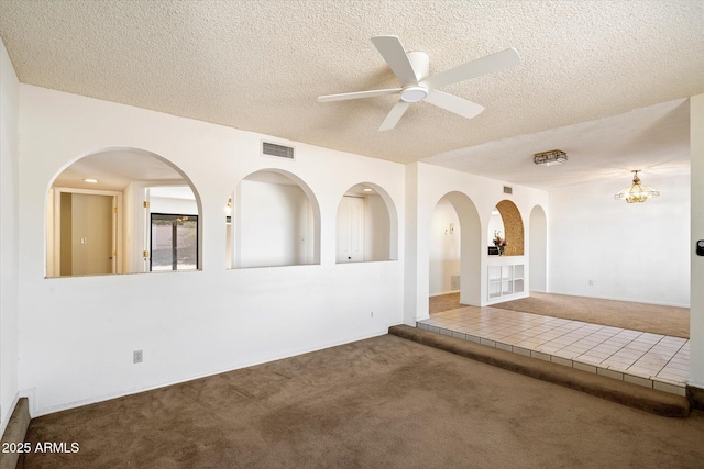 spare room featuring carpet, visible vents, ceiling fan, a textured ceiling, and tile patterned floors