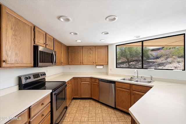 kitchen with light countertops, appliances with stainless steel finishes, a sink, and recessed lighting