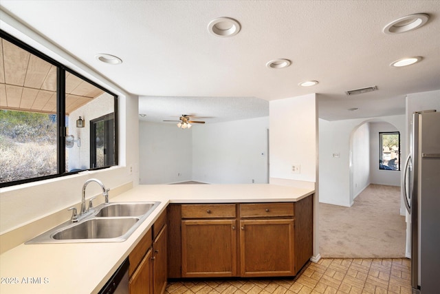 kitchen featuring stainless steel appliances, brown cabinetry, a sink, and visible vents