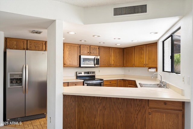 kitchen with a peninsula, visible vents, stainless steel appliances, and a sink