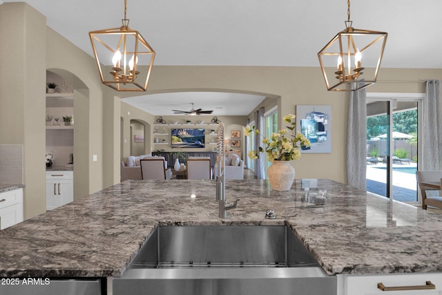 20151 E Via Del Palo St, Queen Creek, AZ 85142 - kitchen featuring a chandelier, arched walkways, ceiling fan, open floor plan, and light stone counters