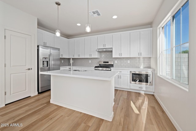 kitchen with stainless steel appliances, a sink, light countertops, and white cabinetry