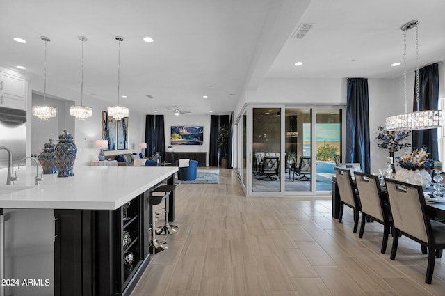 kitchen featuring ceiling fan with notable chandelier, a kitchen bar, stainless steel built in refrigerator, and decorative light fixtures