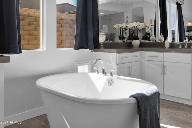 bathroom with a tub to relax in, vanity, and a wealth of natural light