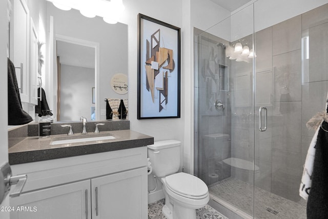 bathroom featuring toilet, vanity, tile patterned floors, and a shower with shower door